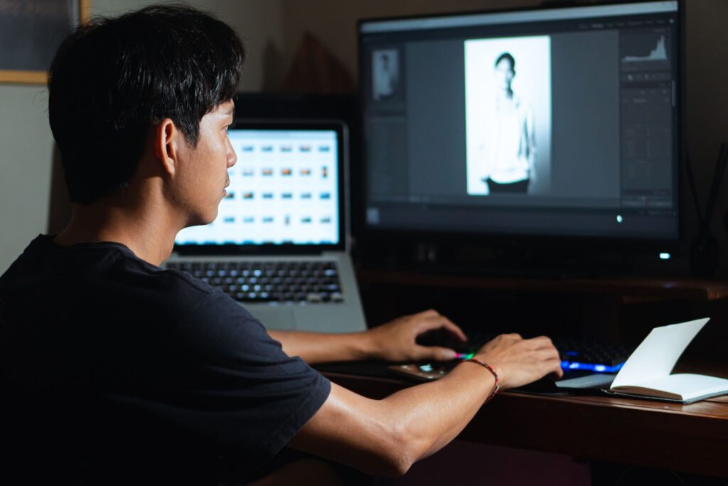 A person editing images on a computer using AI software, a pivotal element of Photography Trends July 2025.
