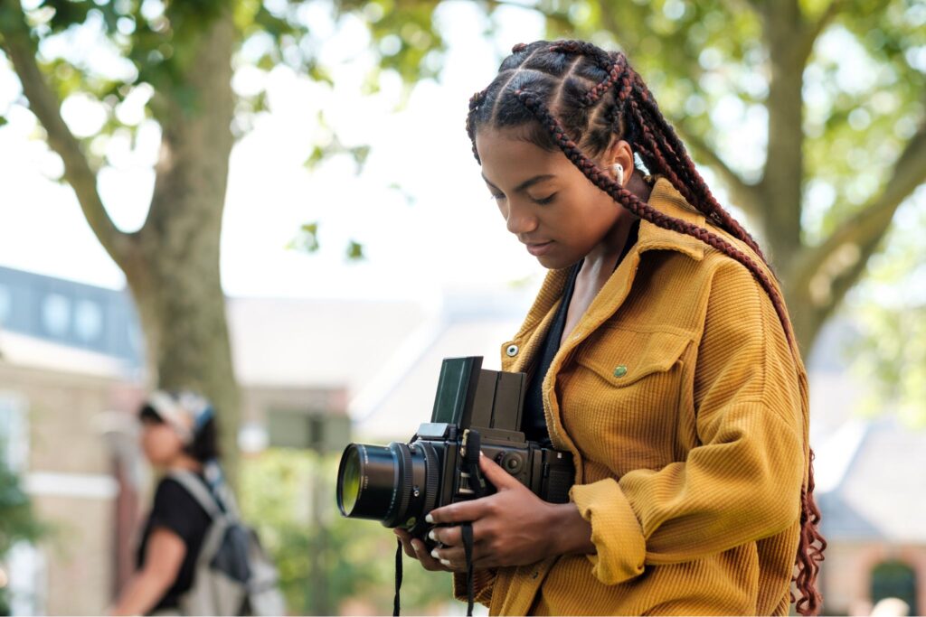 An artist returning to film with a camera in nature, a major theme in Photography Trends July 2025.