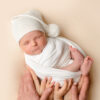 Baby wrapped in a neutral muslin cloth inside a padded basket, demonstrating safe newborn photography posing ideas for beginners.