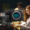 A group of filmmakers setting up cameras and lighting on set, representing creators who could benefit from the Canon EOS C50.