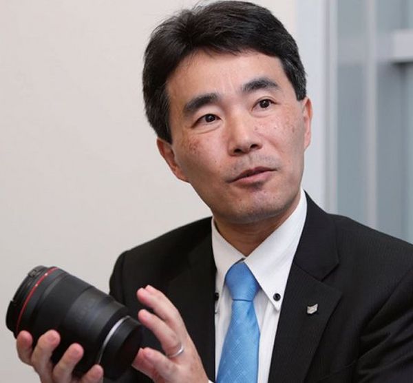 Canon head of product development Manabu Kato holding a Canon lens — the camera that defined photography is turning 50