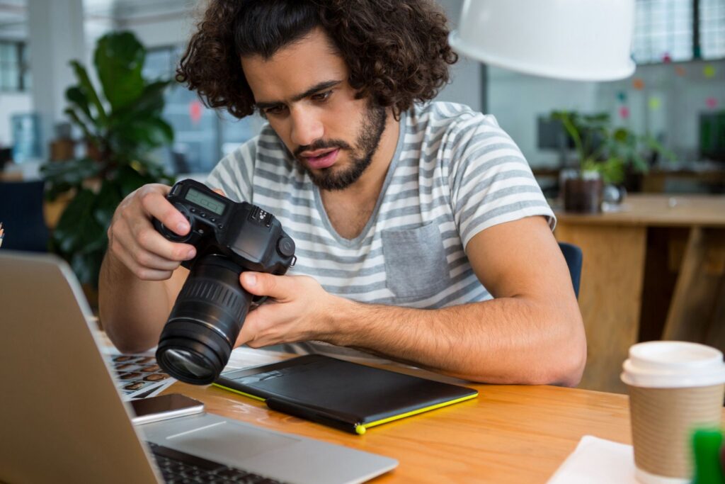 Photographer reviewing camera settings while working at a café — the always-on culture driving photography burnout in the creator economy