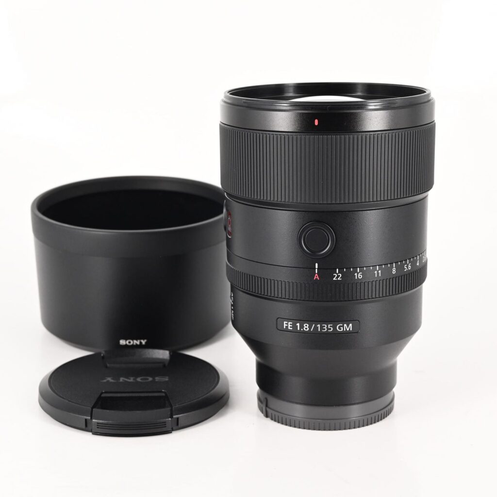 Sony FE 135mm f/1.8 GM lens with lens hood and front cap on white background