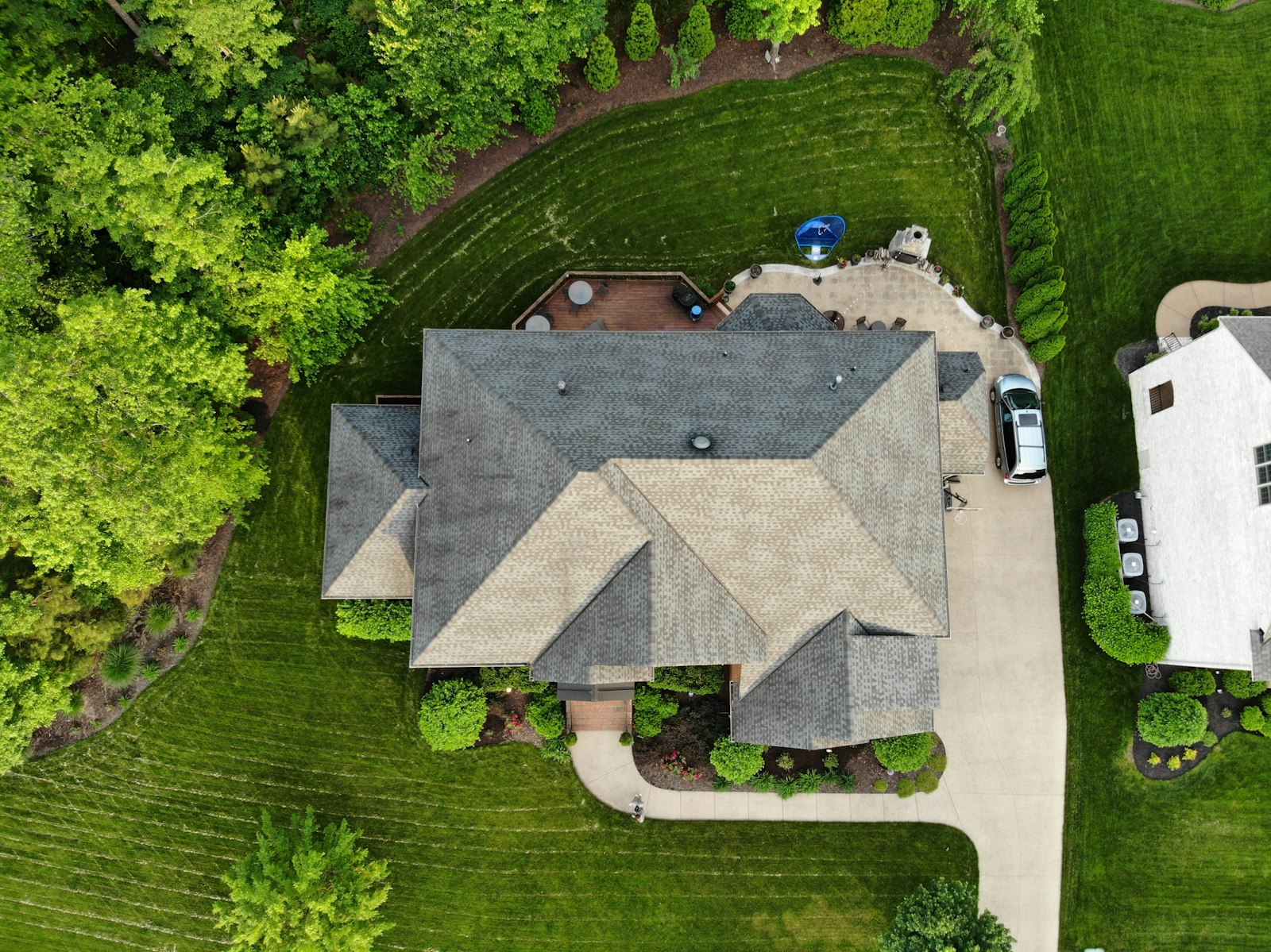 top-down aerial view of a suburban house with driveway surrounded by trees and lawn