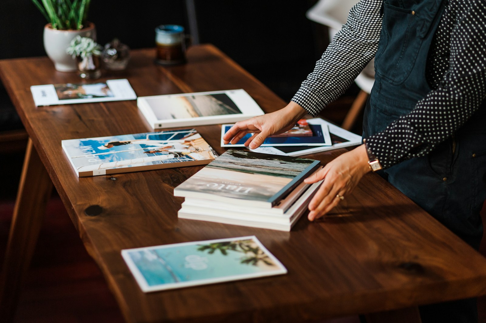 person reviewing photography prints and books arranged on a wooden table