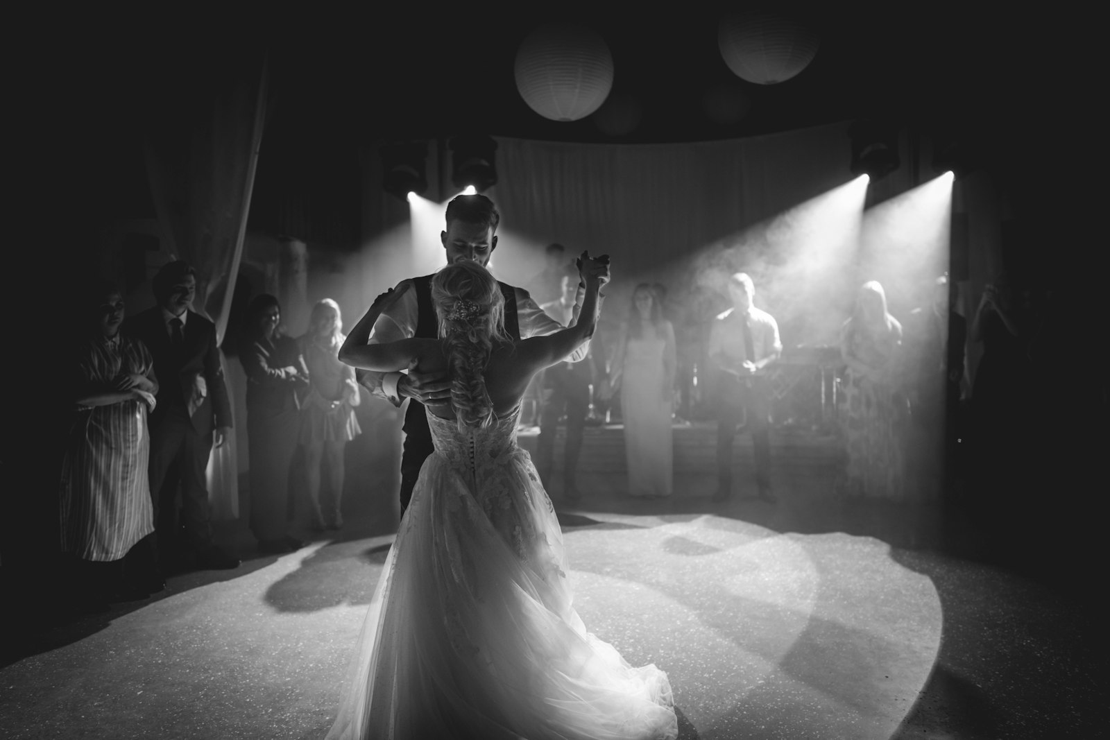 couple dancing in a dimly lit wedding reception with dramatic backlighting