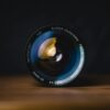 black camera lens standing upright on a wooden surface against a dark background