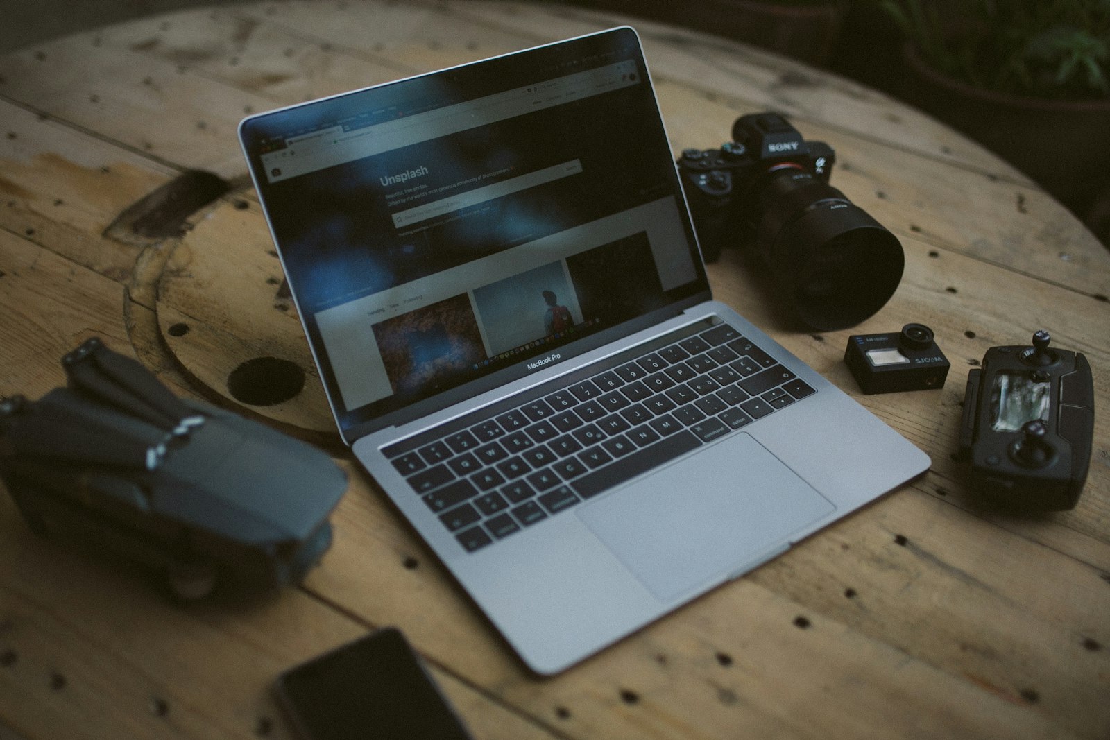 laptop, camera, and photography gear arranged on a wooden table
