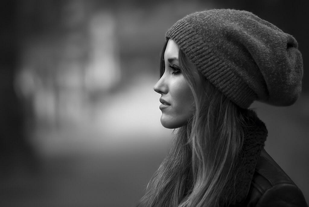 black and white profile portrait of a woman wearing a knit beanie with a softly blurred background
