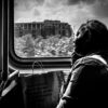 black and white portrait of a woman seated by a bus window with light falling across her face