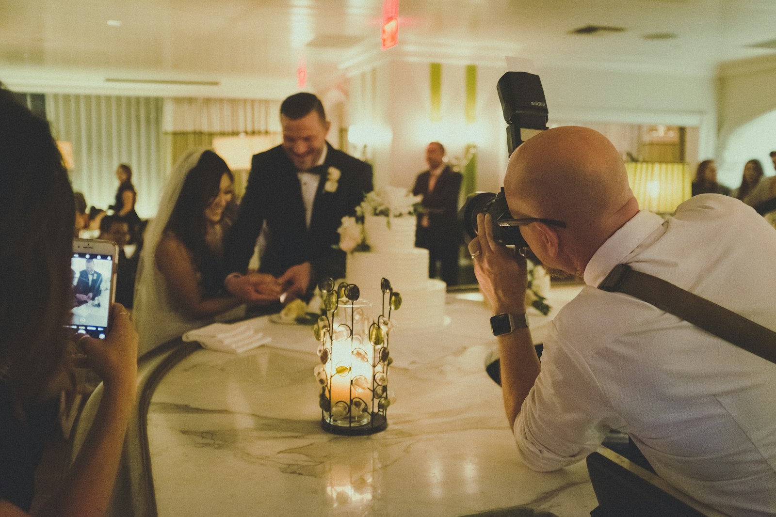 wedding photographer with a DSLR camera photographing a bride and groom at a reception table