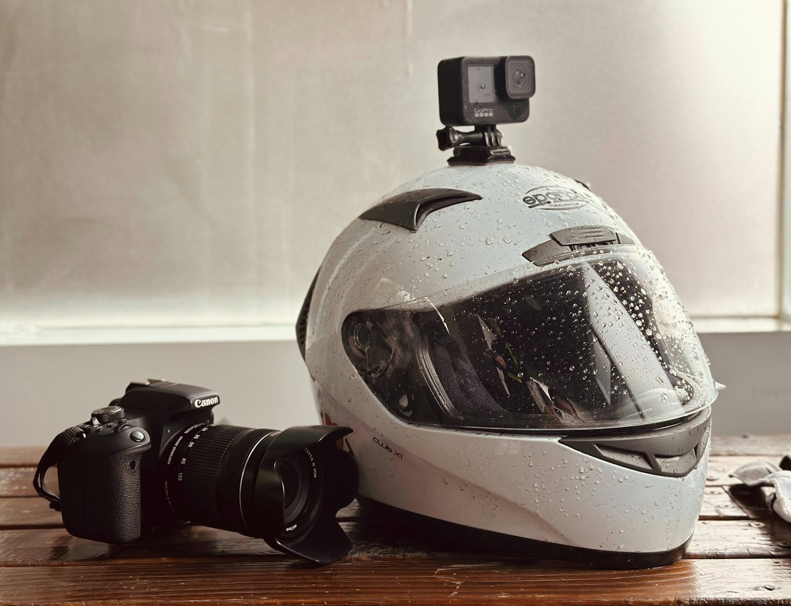 action camera mounted on a white helmet beside a DSLR on a wooden table