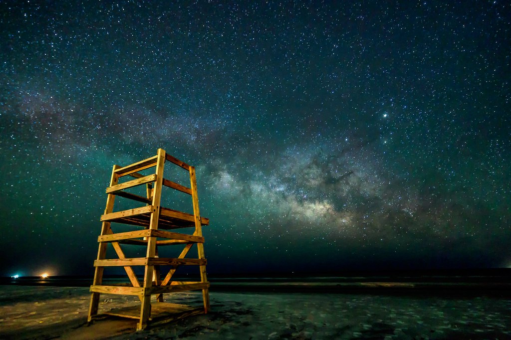 wooden lifeguard chair on a beach under the Milky Way in a star-filled night sky