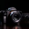 Sony full-frame mirrorless camera with lens and strap on a dark wooden table