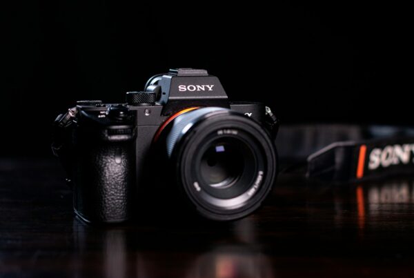 Sony full-frame mirrorless camera with lens and strap on a dark wooden table