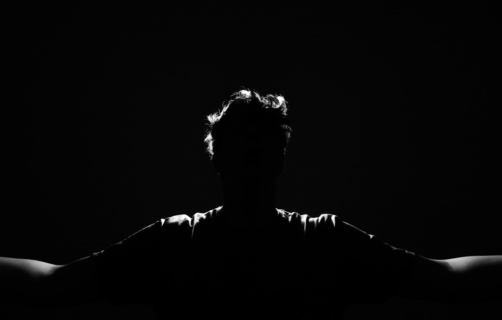 silhouette of a person with arms outstretched, rim-lit against a black background