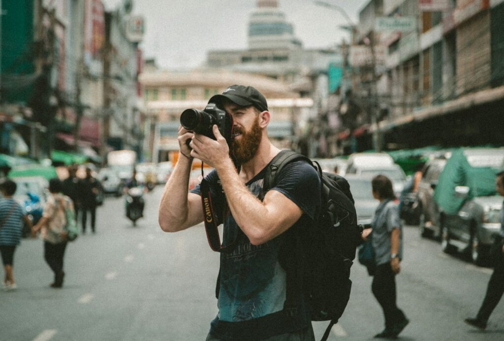 man photographing with a DSLR camera on a busy city street