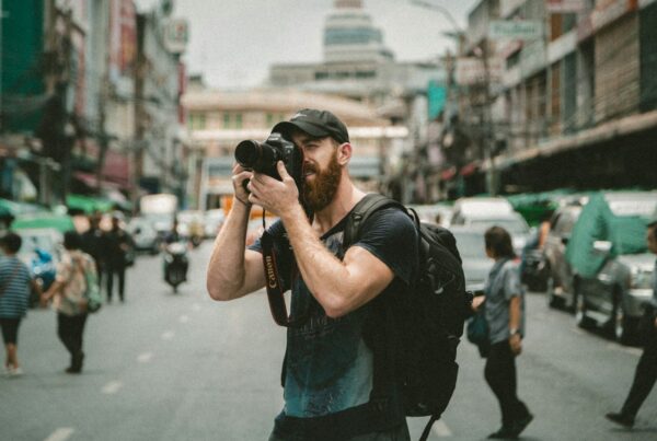 man photographing with a DSLR camera on a busy city street
