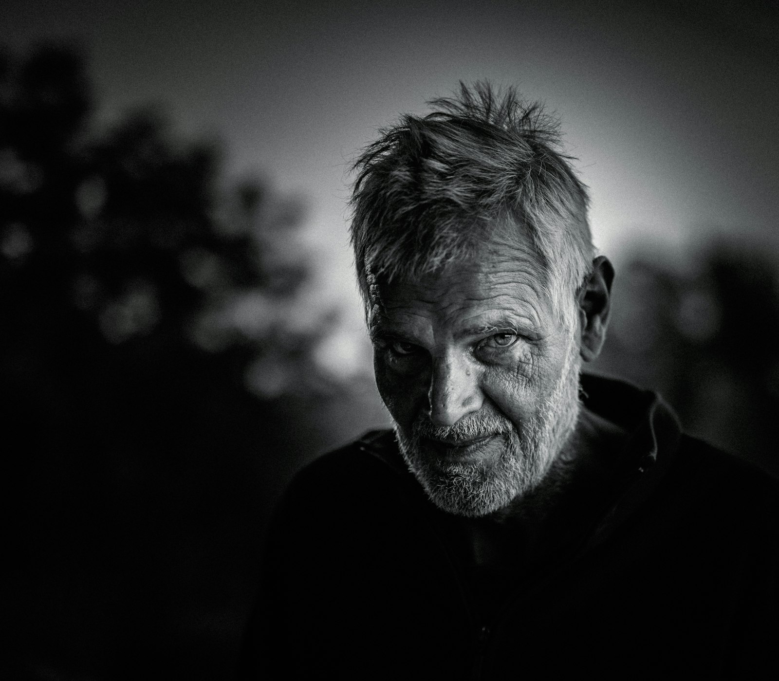 black and white portrait of an older man outdoors with hard side lighting and deep shadows