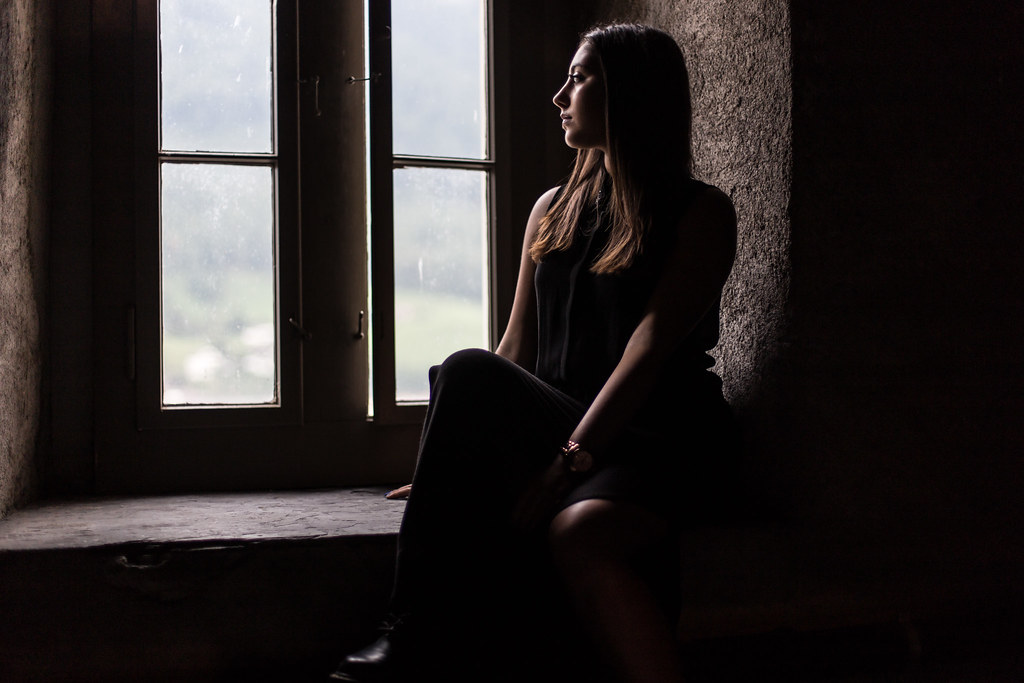 woman seated by a window indoors with soft directional light illuminating her profile