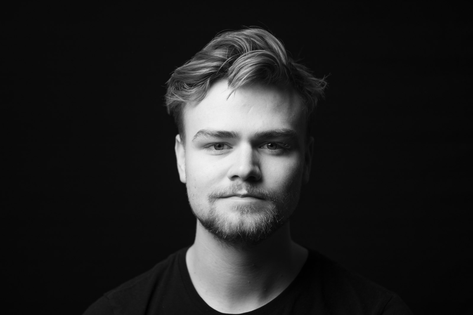 black-and-white portrait of a bearded man against a dark background with side lighting