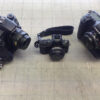 three cameras of varying sizes arranged side by side on a gridded neutral surface