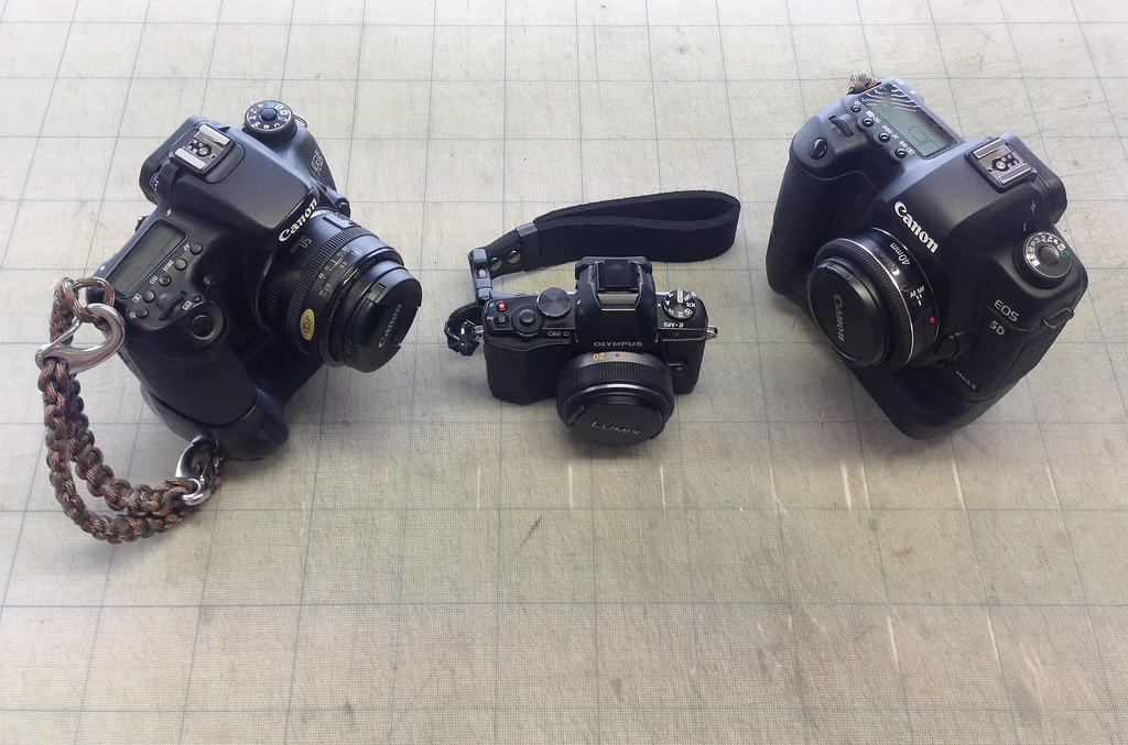 three cameras of varying sizes arranged side by side on a gridded neutral surface
