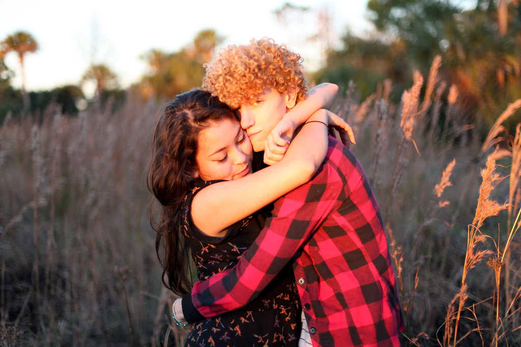 couple embracing in a grassy field during golden-hour sunlight