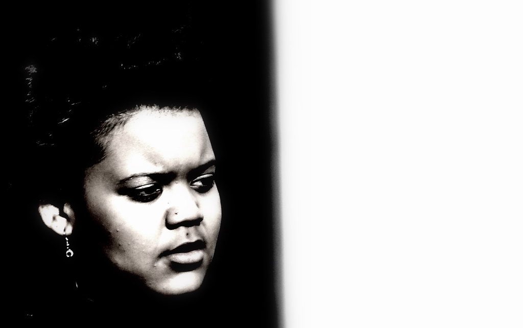 black and white portrait of a woman's face lit from one side against a dark background