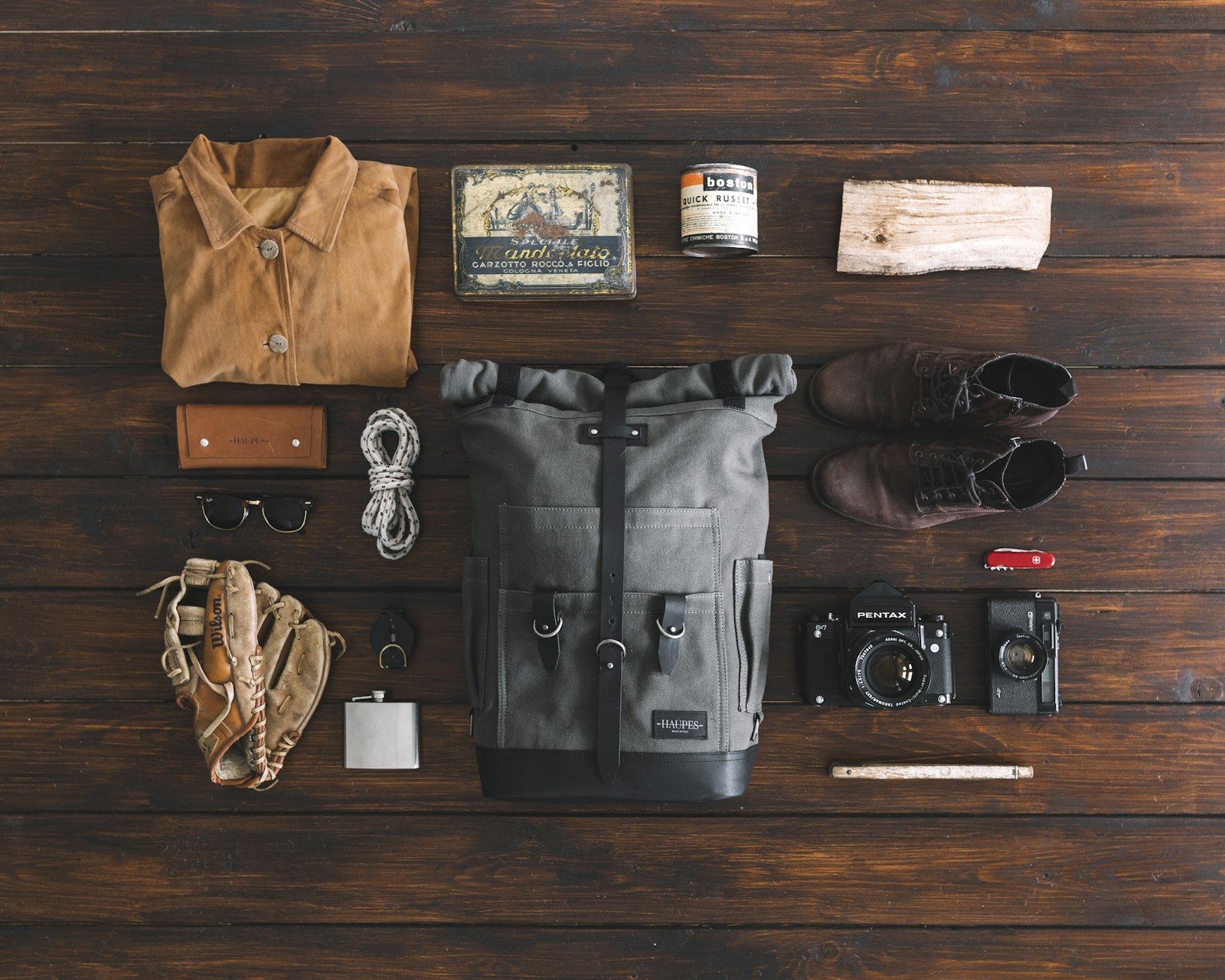 camera bag laid flat with a camera, lens, and travel accessories on a wooden surface